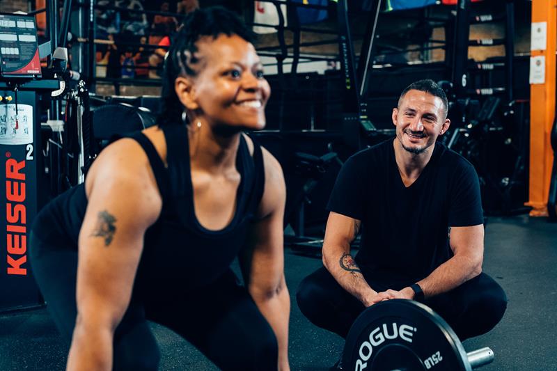 Lukasz coaching a client through a strength exercise at the gym